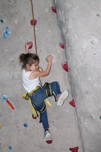 A child tries an indoor climbing wall during an outing